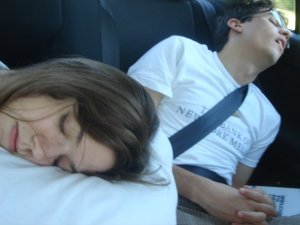 A photo of two people sleeping in the back of a car